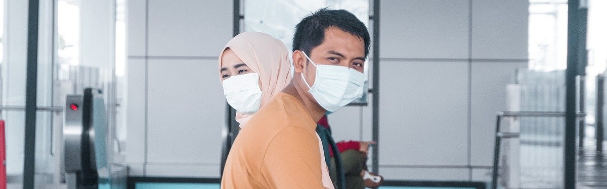 Two people in a train station wearing masks