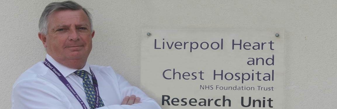 Image of patient stood next to Hospital sign